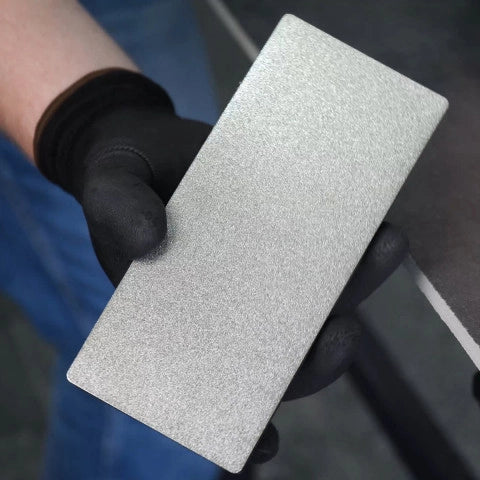 Hand holding a Distar sanding block with a textured surface, wearing a black glove.